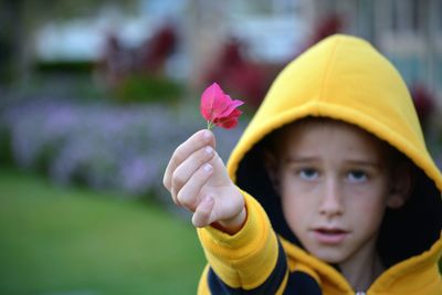 Portrait of boy holding pink flower