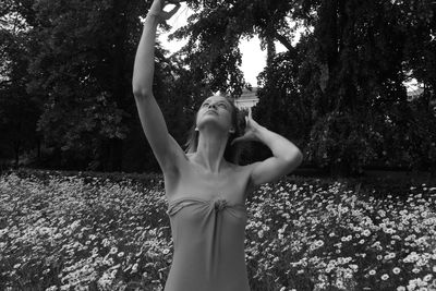 Young woman standing against flowers at park