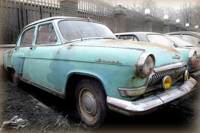 Old rusty car on street in city