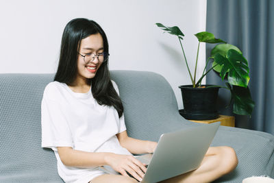 Young woman using mobile phone while sitting on table