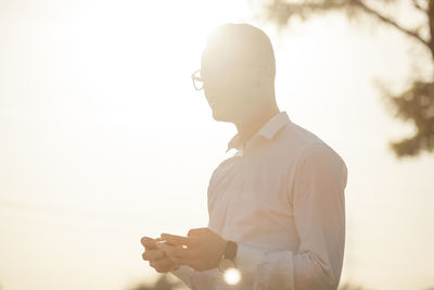 Man holding mobile phone against sky