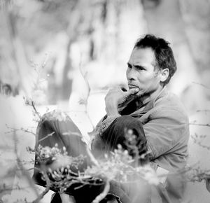 Portrait of young man looking at flower plants