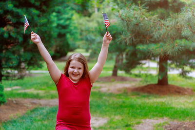 Portrait of smiling girl holding smart phone while standing outdoors