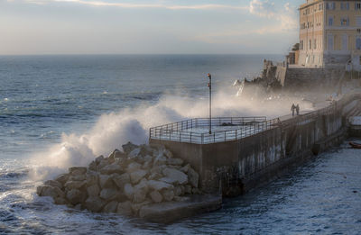 Scenic view of wave of sea on pier against sky