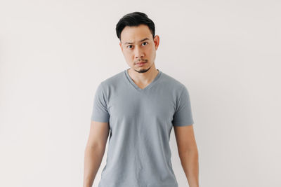 Portrait of young man standing against white background