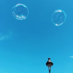 Low angle view of bubbles against blue sky