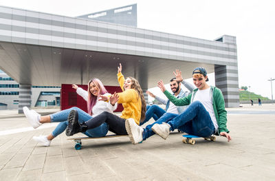 Cheerful friends sitting on skateboard