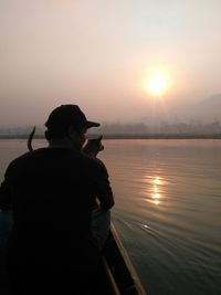 Rear view of man photographing at sunset