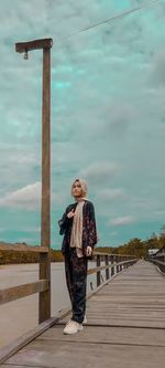 Woman standing on footpath against sky