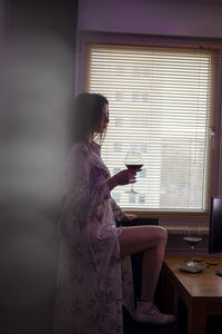 Side view of woman sitting on table at home