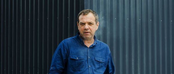 Portrait of man standing against corrugated iron