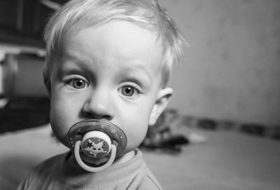 Portrait of cute baby boy with pacifier at home