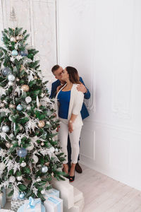 Couple kissing while standing by wall at home