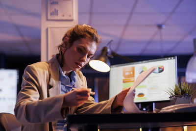 Portrait of young woman using mobile phone while sitting on table