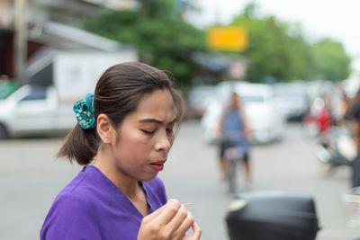 Mid adult woman looking down while standing on road in city