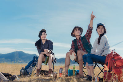 Friends sitting on chairs against sky