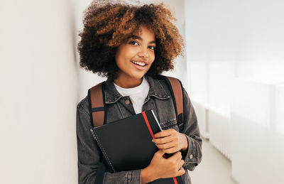 Afro student leaning on wall