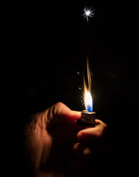 Cropped image of hand holding lit candle