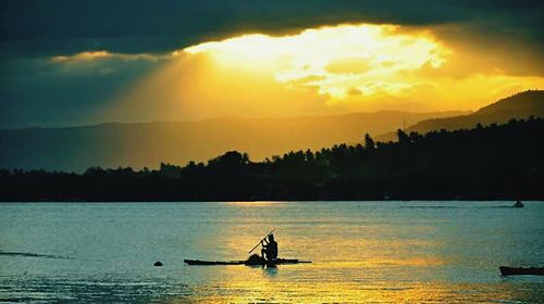 Silhouette of boat in sea at sunset