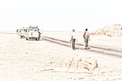 Rear view of people walking on beach