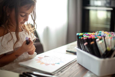 Cute girl drawing on paper at home