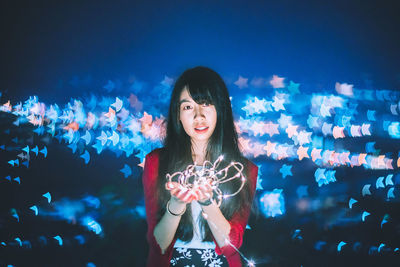 Portrait of smiling young woman standing at night