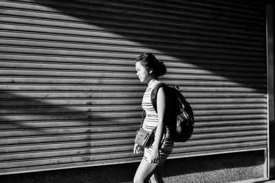 Side view of woman standing against shutter