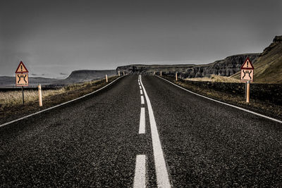 Road leading towards mountain against clear sky