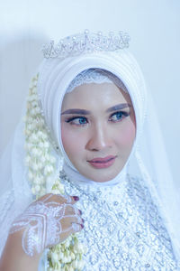 Portrait of young woman wearing hijab against white background