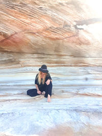 Woman wearing casual black clothes sitting on sandstone