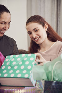 Excited girl looking at birthday present while sitting with mother at home