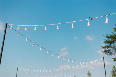 Low angle view of light bulbs hanging against sky