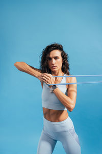 Portrait of woman exercising against blue background