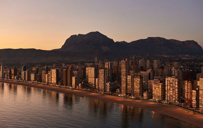 Illuminated cityscape against sky at sunset