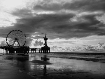 Ferris wheel by sea against sky