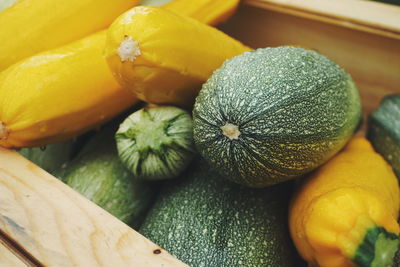 High angle view of wet yellow and green squash in wooden basket for sale at market