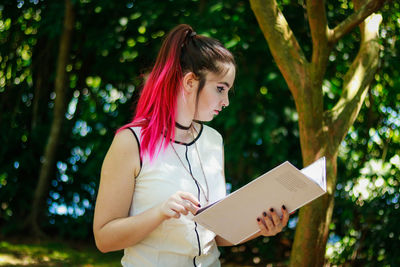 Woman reading file while standing at park