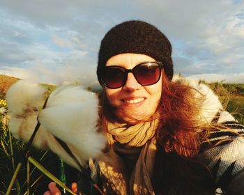 Portrait of smiling young woman wearing sunglasses against sky