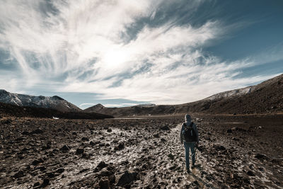 Rear view of man walking on mountain against sky