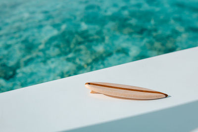 High angle view of small surfboard against swimming pool