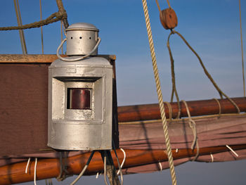Close-up of lantern by rope on boat against sky