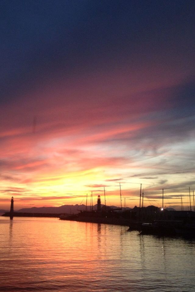 sunset, water, silhouette, scenics, orange color, waterfront, tranquil scene, cloud, tranquility, calm, sky, idyllic, reflection, beauty in nature, nature, dramatic sky, cloud - sky, sea, ocean, majestic, outdoors, outline, sun, commercial dock, development, no people, moody sky, tall