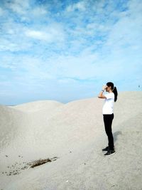 Full length of woman standing on sand against sky