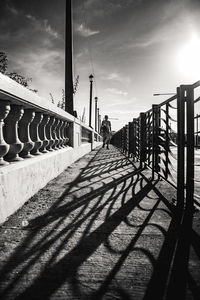 Shadow of woman walking on bridge against sky