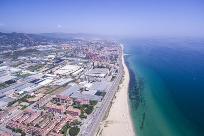 Aerial view of city by sea against blue sky