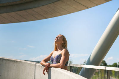 Low angle view of young woman standing against sky