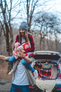 Man carrying girlfriend on shoulder in forest