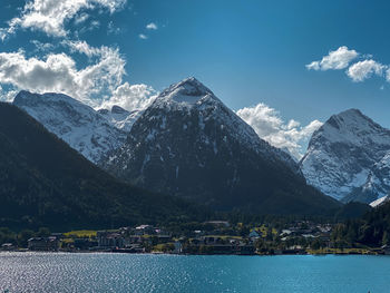 Scenic view of lake by snowcapped mountains against sky