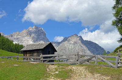 Built structure on field by mountain against sky