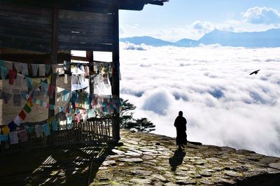 Rear view of man standing on mountain against sky